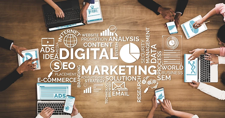 Set of text related to digital marketing in the middle of a table surrounded by marketers working on strategies